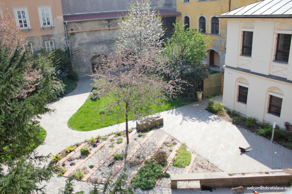 On the left side of the bridge there is a small green park surrounded with old buildings